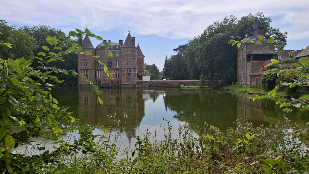 Le magnifique château d'Anvaing se reflète dans l'étang, au milieu d'un écran de verdure